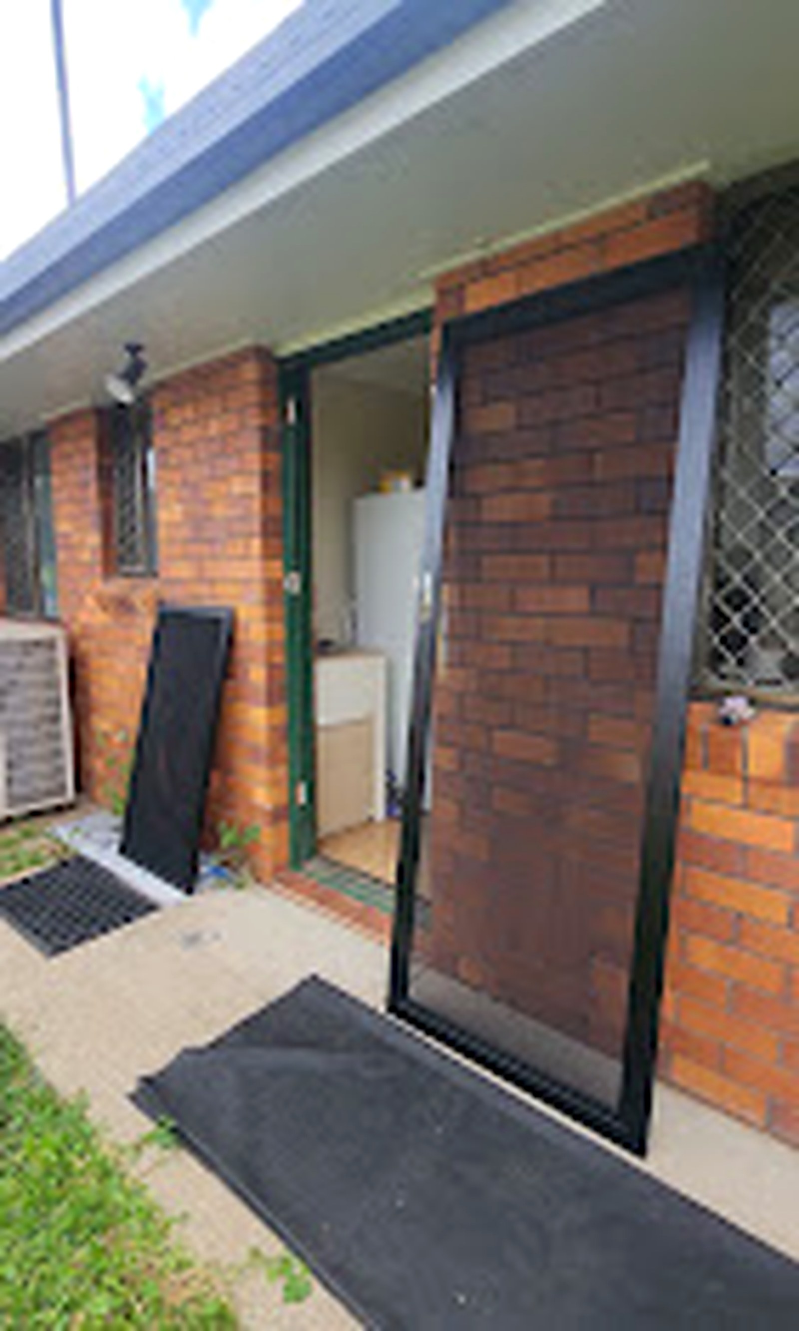 Finished full-height security screen door beside a brick wall