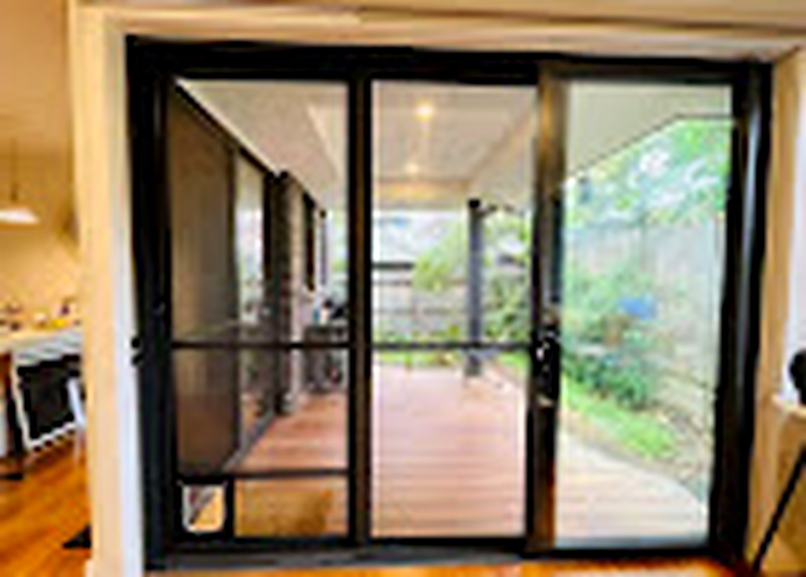 Wide black sliding screen installation opening onto a deck