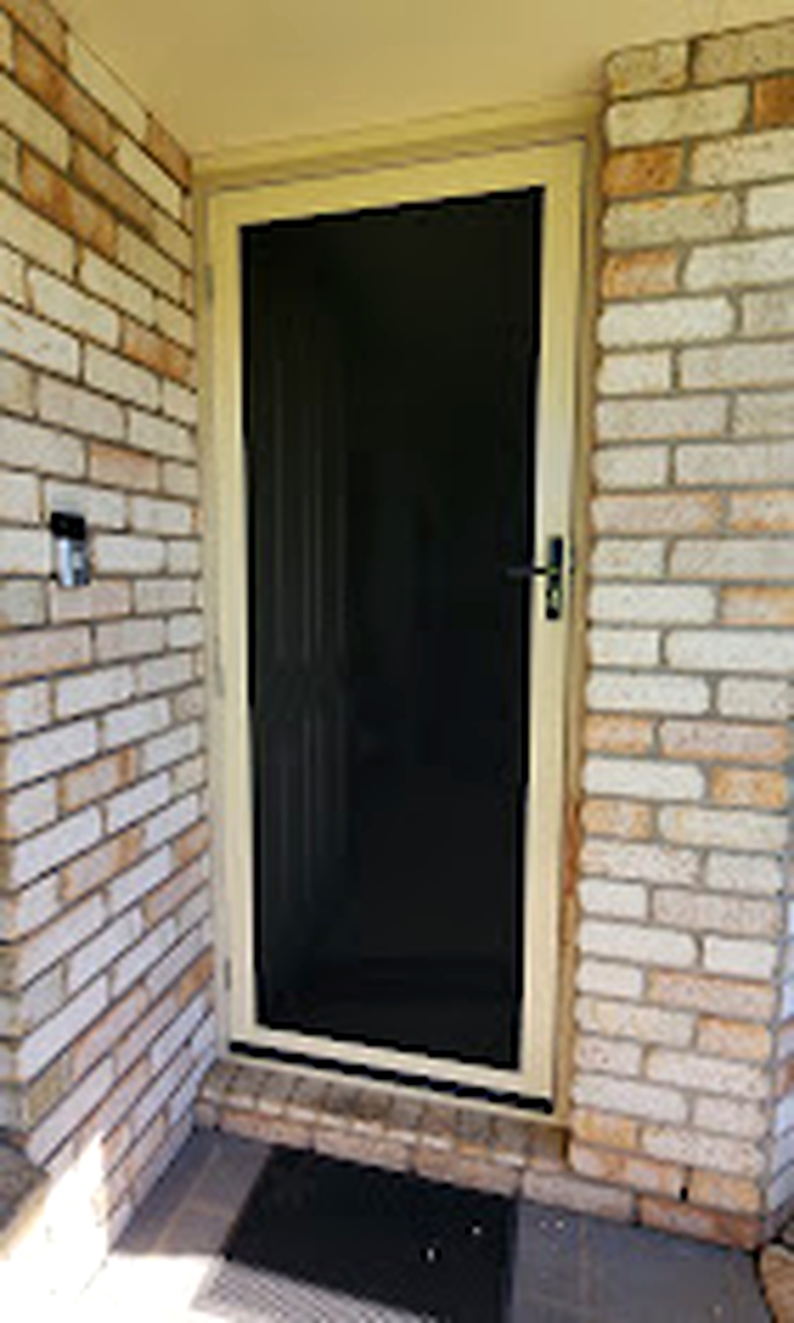 Black mesh entry door professionally fitted to a brick home